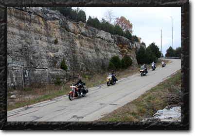 Five bikers riding down a hilly road