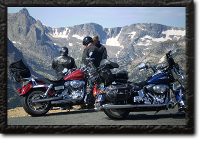 Three bikers take a break with the Colorado Mountains in the distance